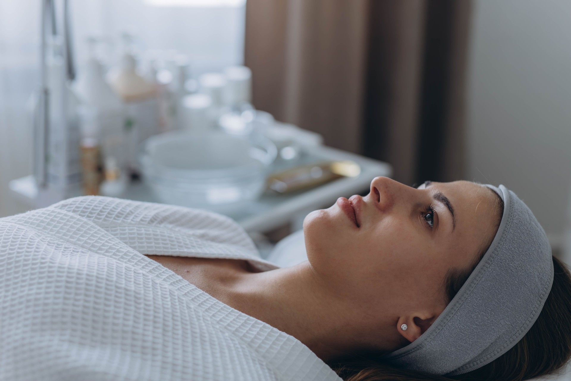 Young woman cleaning face skin in salon. Retinol peel with brush. Acid organic peeling.