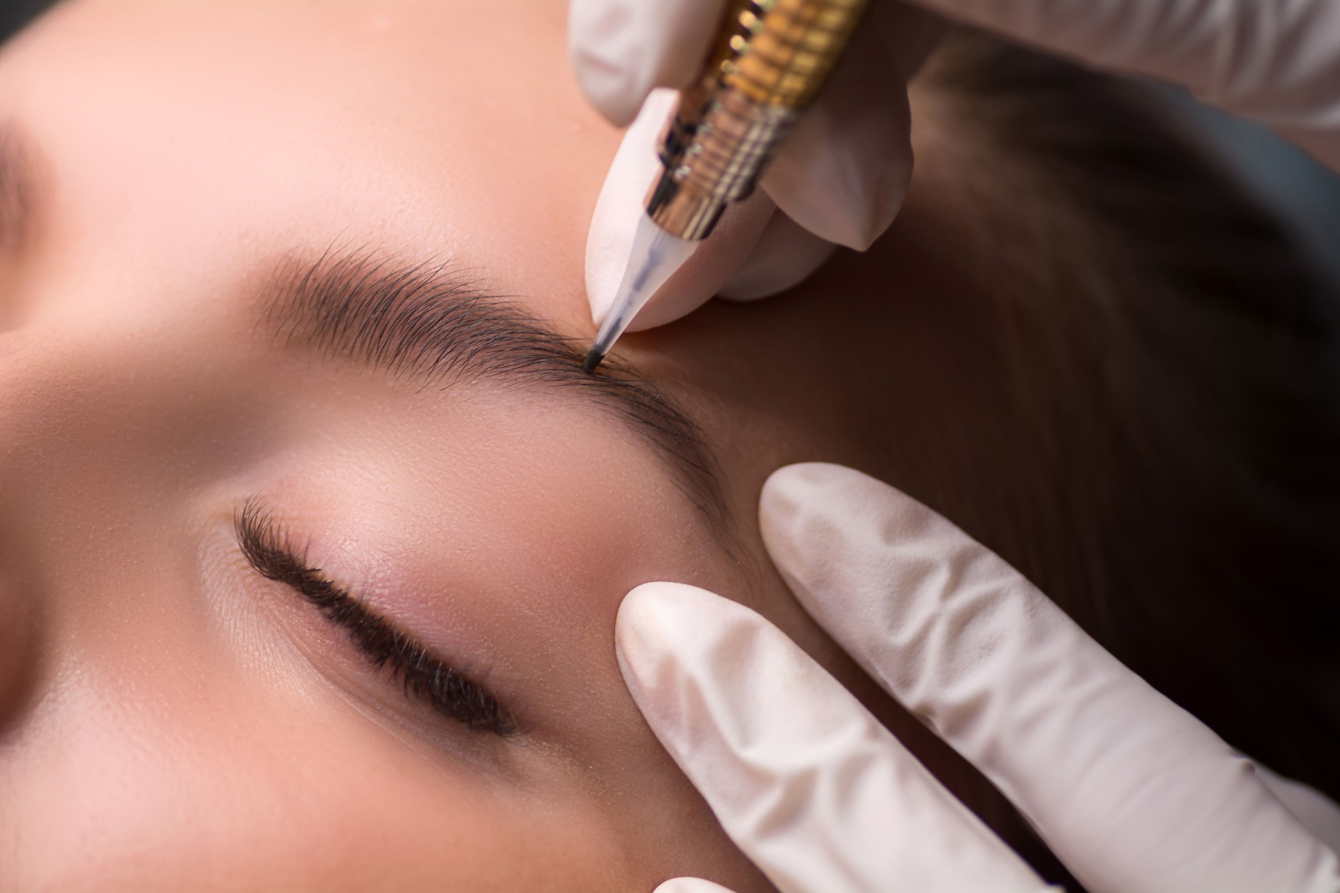 Permanent eyebrow makeup. Cosmetologist applying tattooing of eyebrows.